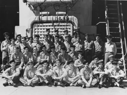 Group of military personnel in uniforms posing in front of a building and stairs, black and white photograph.