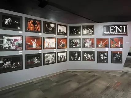 Wall displaying black-and-white and color concert photographs arranged in a gallery setting.