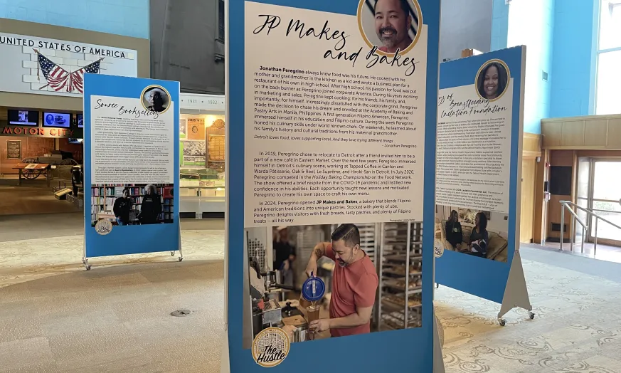 Exhibit panels with text and photos stand in a spacious room with light walls and windows.