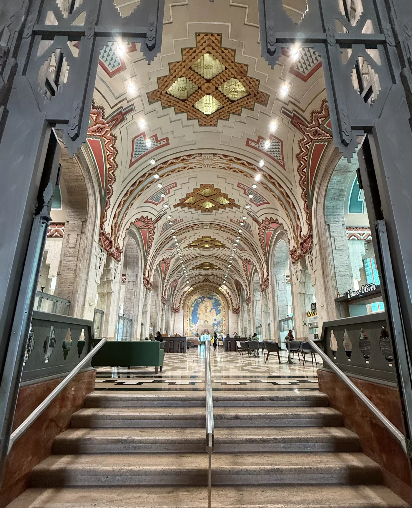 Ornate interior with arched ceiling, decorative patterns, and a staircase leading to a bright hall.