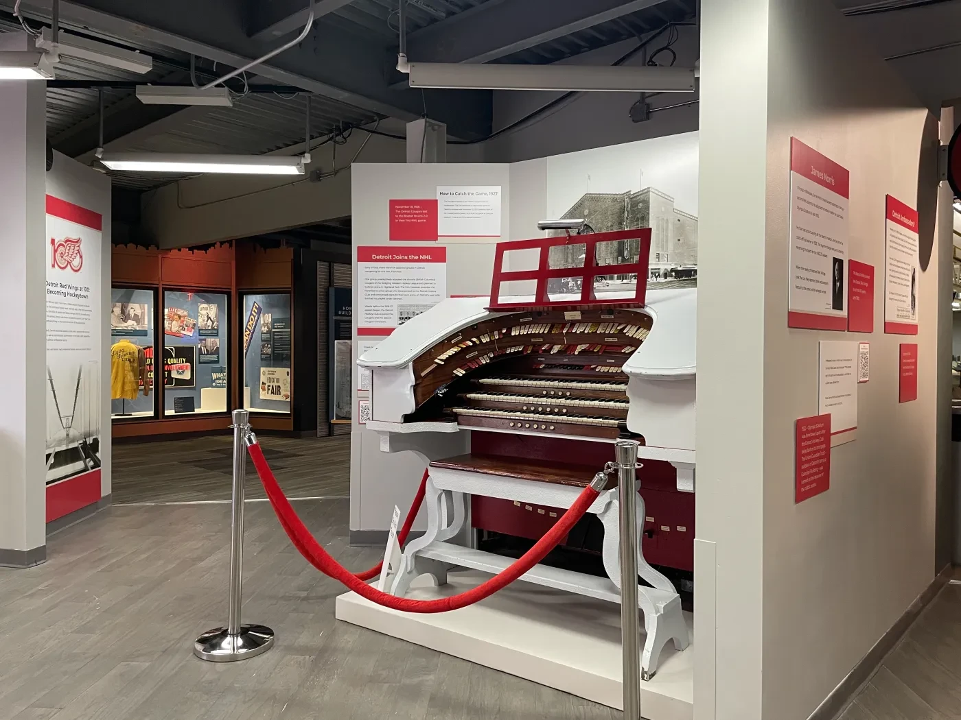 Antique organ displayed in a museum exhibit with red rope barrier.
