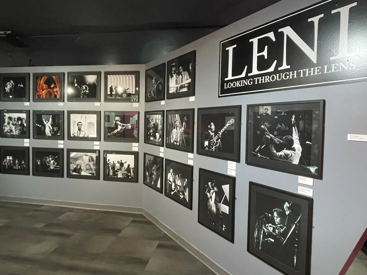 Black and white photo exhibition on a gray wall, featuring various historical and artistic images.