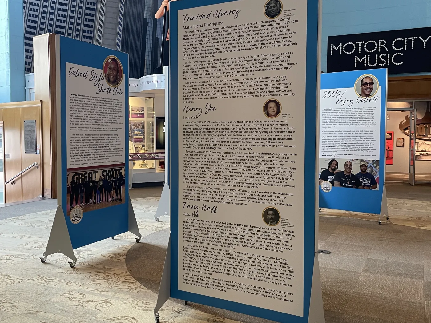 Three informational panels with text and photos in a museum setting, one labeled "Motor City Music" in the background.