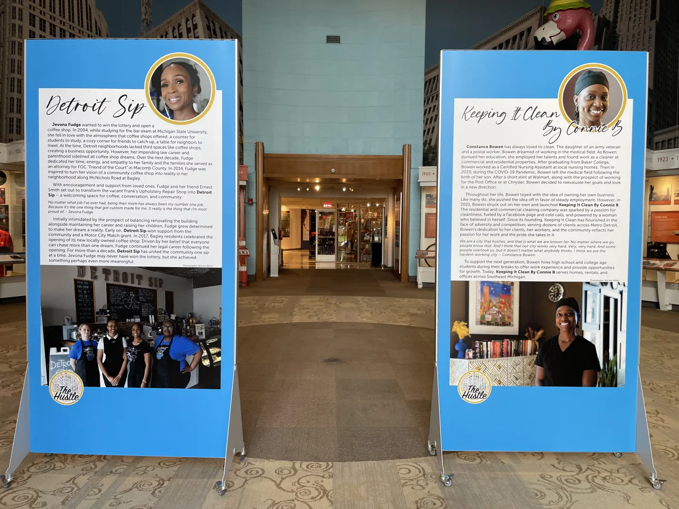 Exhibit with two blue information panels featuring photos and text, displayed in a spacious indoor area.