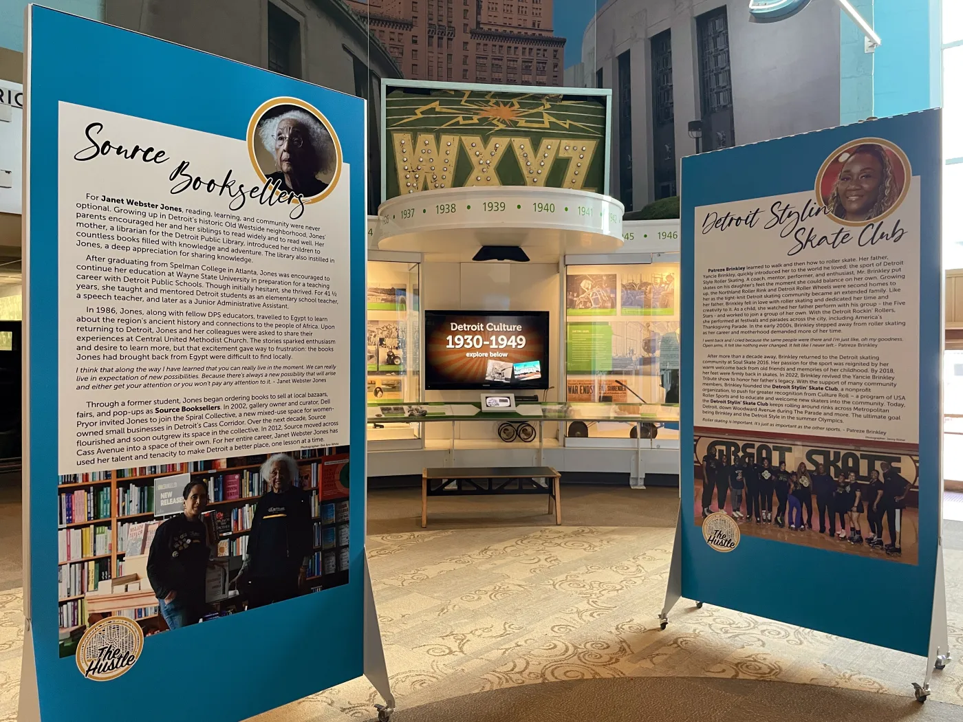 Exhibit with two large info panels and a vintage TV station setup in the background.