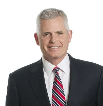 Smiling man in suit with striped tie on white background.