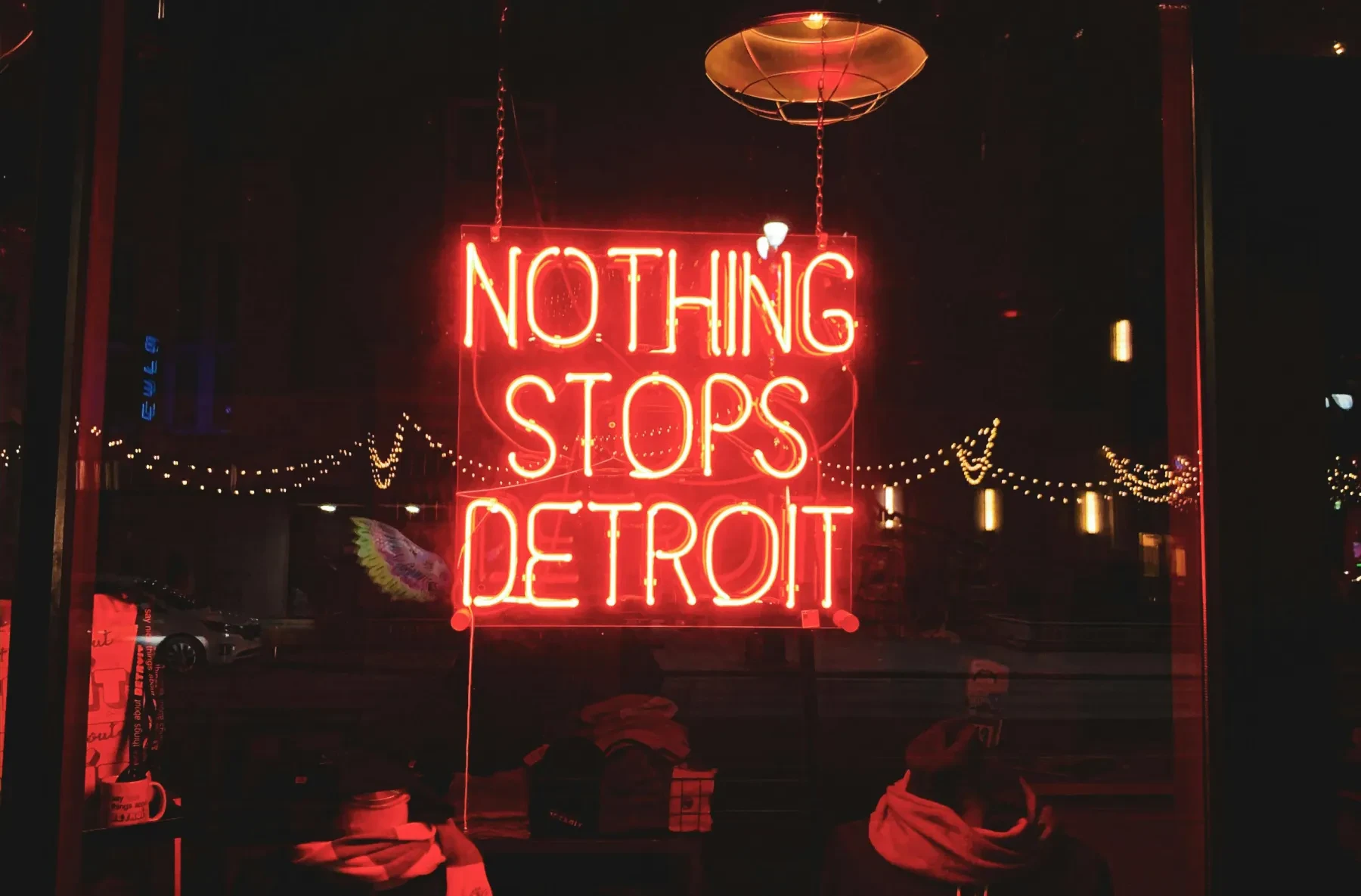 Neon sign reading "NOTHING STOPS DETROIT" in red, with a dark street and lights in the background.